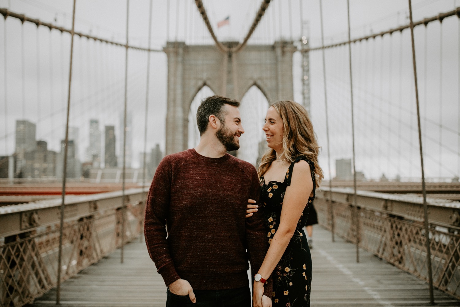 Couple standing in the middle of a bridge looking at each other and smiling.